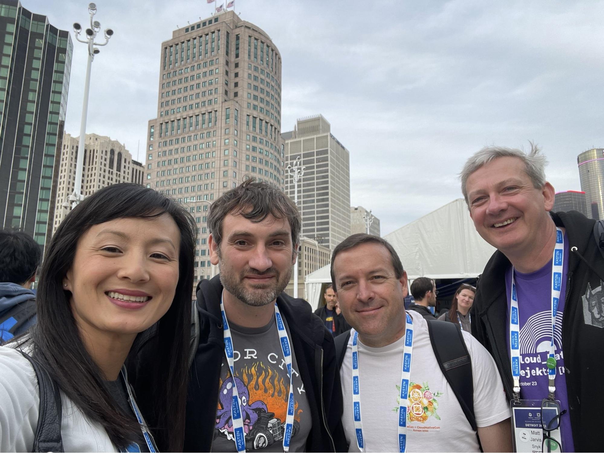Selfie picture with Betty Junod, Adrian Mouat, Eric Smalling, and Matt Jarvis standing with skyscrapers behind them. Taken during Kubecon North America 2022 in Detroit, MI